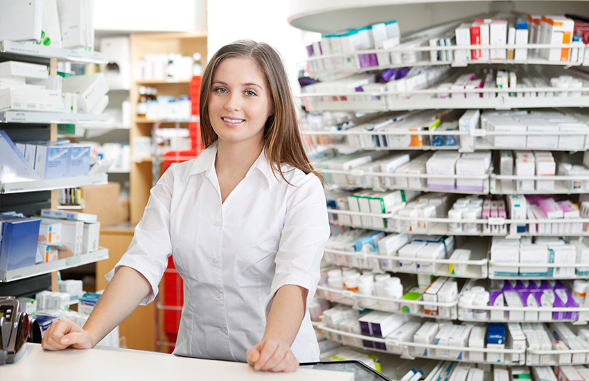 Farmac&eacute;utica con los brazos apoyados en el mostrator sonr&iacute;e