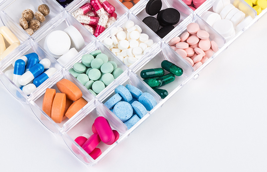 Caja abierta con compartimentos llenos con pastillas de diferentes colores